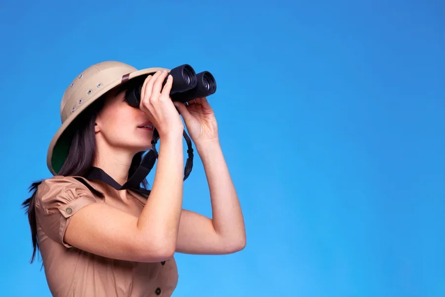 Woman in hat searching with binoculars