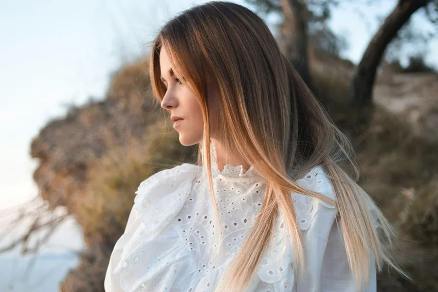 Woman with a blond straight hair in a white dress.
