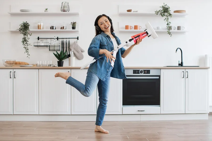 Frauen tun so, als würden sie auf einem Staubsauger wie auf einer Gitarre spielen