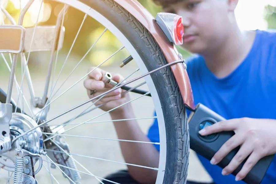Anak laki-laki memasang pompa sepeda pintar untuk membaca tekanan ban