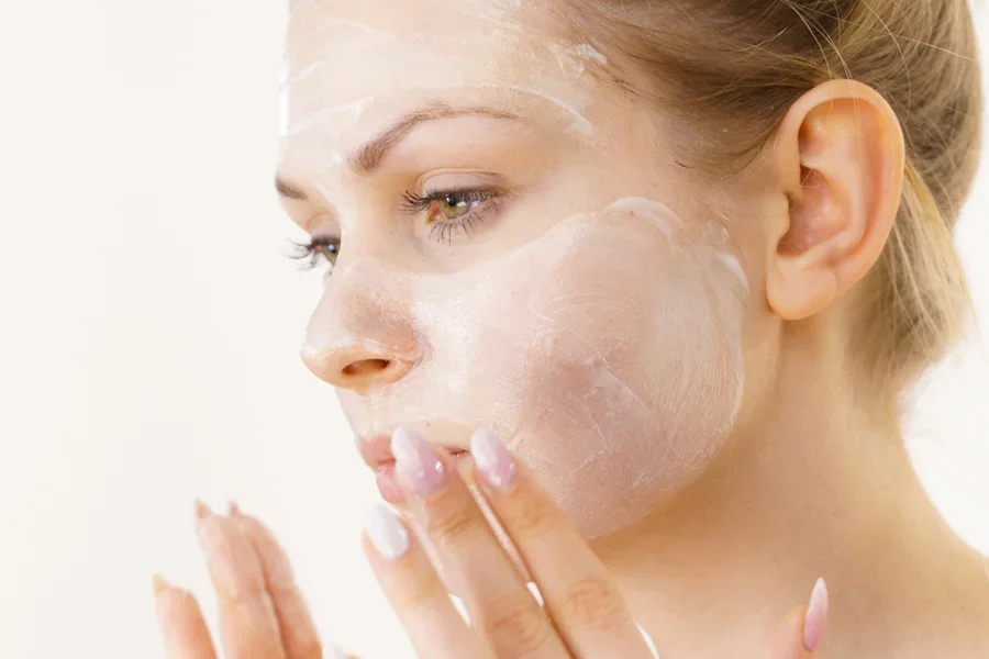 Junge Frau trägt kleine Mengen Creme auf, um Rötungen zu reduzieren