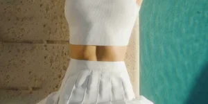 a woman in a white dress standing next to a wall