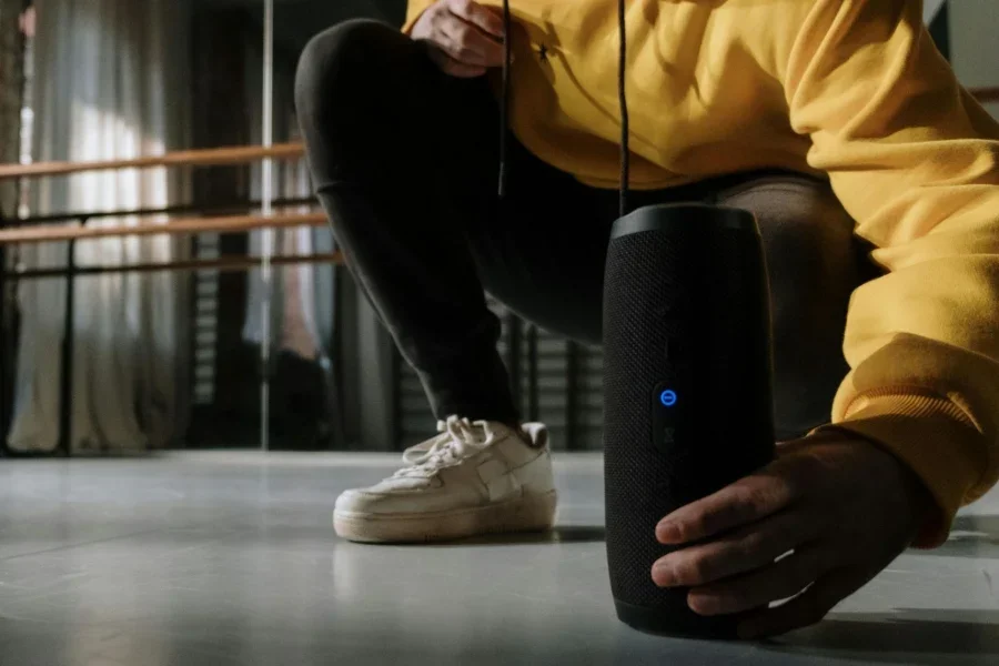 Человек в желтом свитере кладет беспроводную колонку на пол