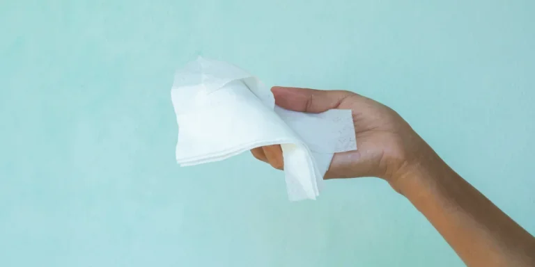 Una persona sosteniendo toallitas húmedas sobre un fondo azul.