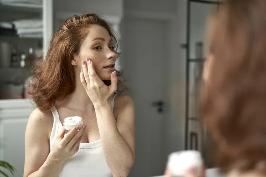 A woman applying facial cream