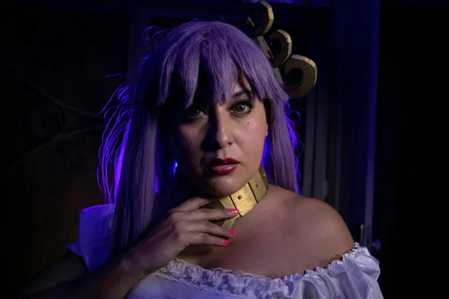 Eine Frau in einem Fantasy-Cosplay mit lila Haaren und dramatischer Beleuchtung