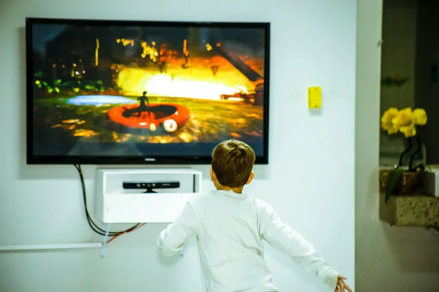 Un niño pequeño observa intensamente e interactúa con un videojuego en una pantalla de televisión en el interior.