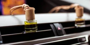 Car air perfume freshener bottles inside the car on car panel. Aromatic liquid in the small bottle