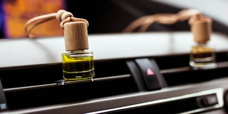 Car air perfume freshener bottles inside the car on car panel. Aromatic liquid in the small bottle