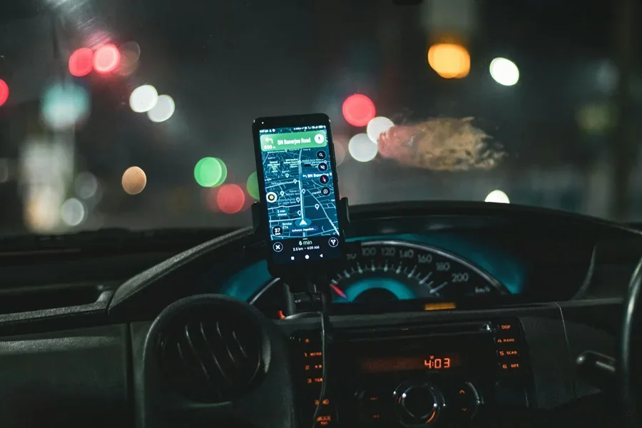Primer plano de un teléfono inteligente con navegación de mapas en un automóvil por la noche con efecto bokeh