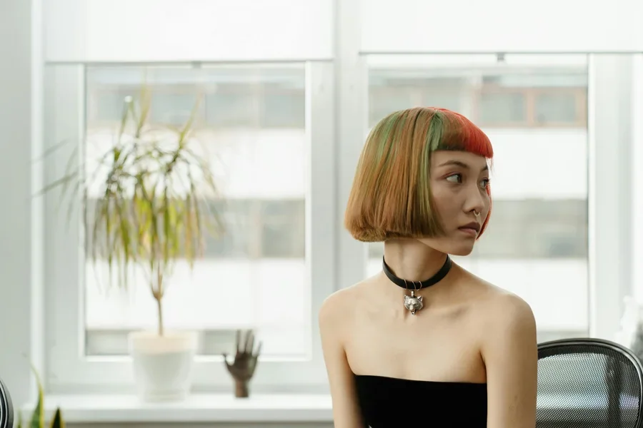 Elegante mujer asiática con cabello colorido en un moderno estudio de tatuajes lleno de luz natural.