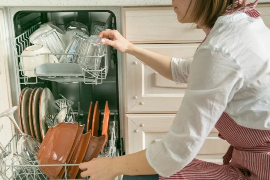 Female Takes the Dishes from Dishwasher