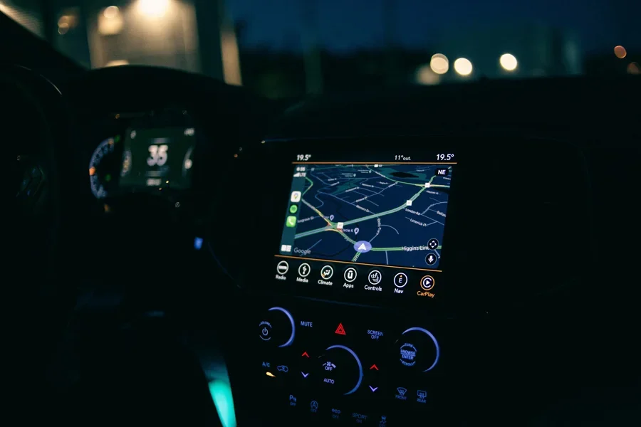 Vista interior de un automóvil con sistema de navegación GPS iluminado por la noche, mostrando tecnología y viajes modernos.