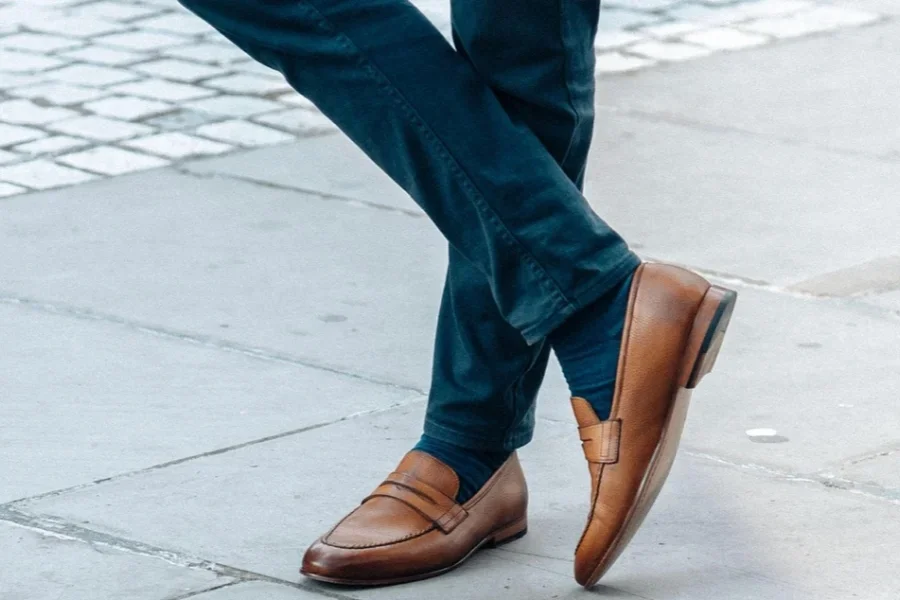Homem usando sapatos de couro e cruzando as pernas na rua