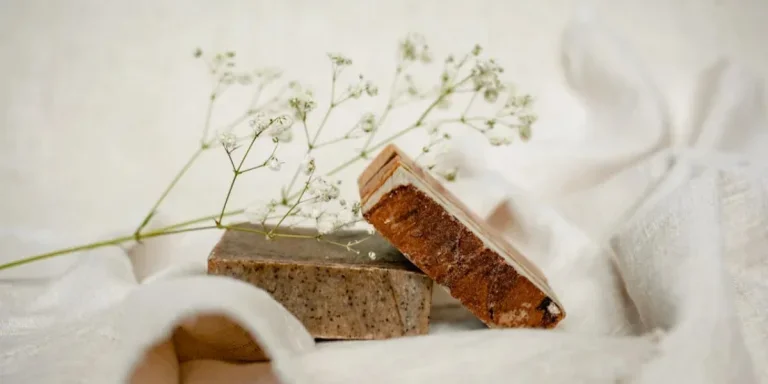 Jabones naturales en tonos óxido y marrón sobre fondo de tela blanca.