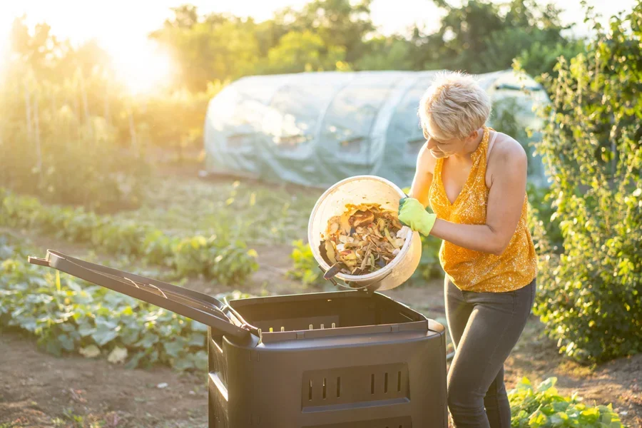 Person dumping food scraps into an outdoor compost bin