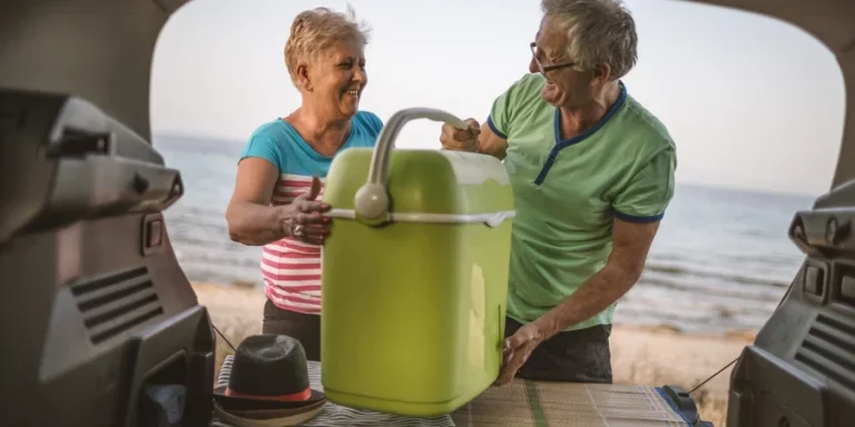 Un couple de personnes âgées remplit le coffre d'une voiture pendant les vacances d'été
