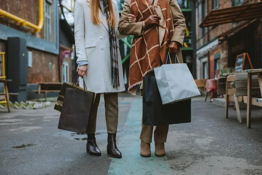 Dos mujeres sosteniendo bolsas de compras y usando botas