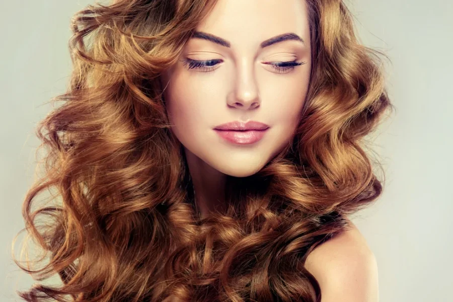 Los rizos voluminosos enmarcan el rostro con suave elegancia.