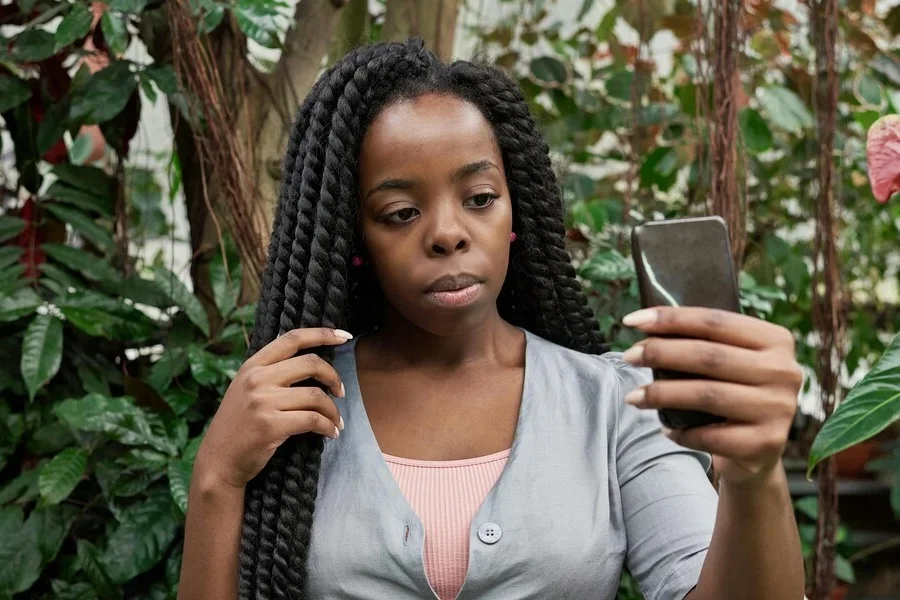 Женщина в защитной прическе делает селфи