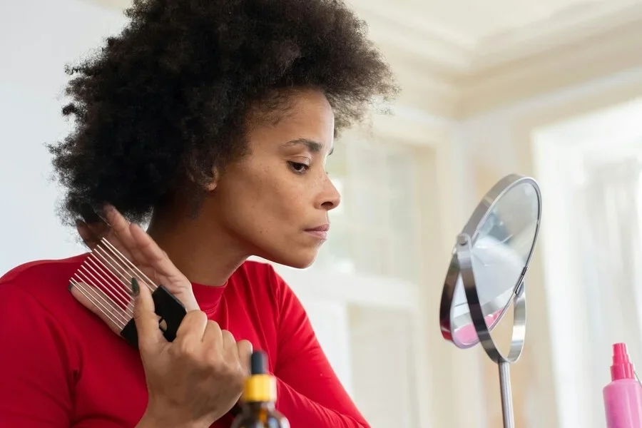 Женщина укладывает волосы расческой