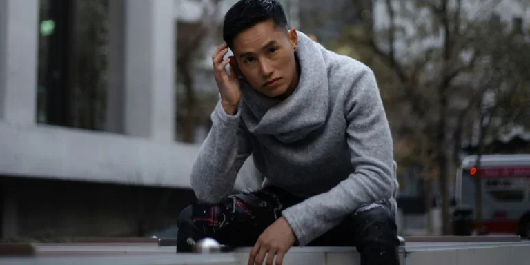 Young Asian man on gray shirt sitting on a fence