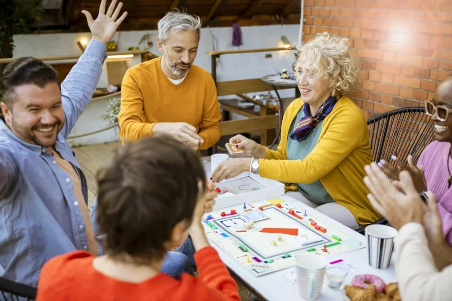 Junge Erwachsene und ältere Menschen spielen fröhlich lustige Brettspiele