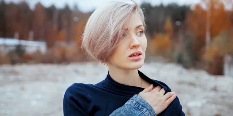 Una mujer con cabello rubio platino parada en un campo