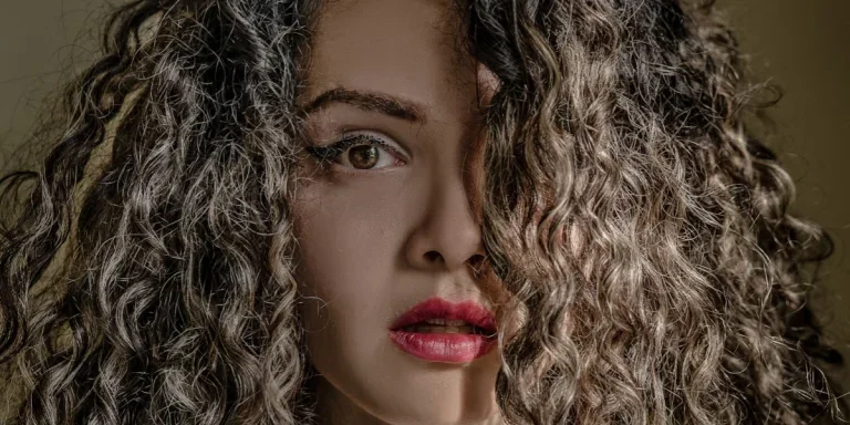 Dama posando con la mitad de la cara cubierta de pelo rizado