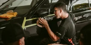 A man meticulously polishes a car, showcasing precision in an automotive workshop