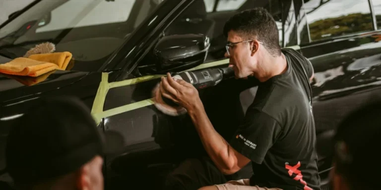 Ein Mann poliert sorgfältig ein Auto und stellt damit Präzision in einer Autowerkstatt unter Beweis