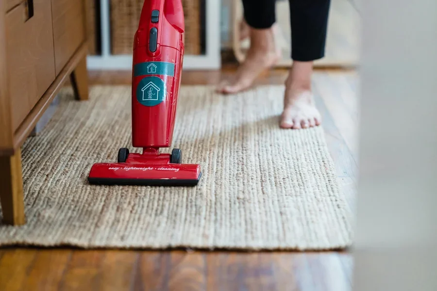 A red vacuum cleaner on a carpet in a stylish home setting with barefoot user