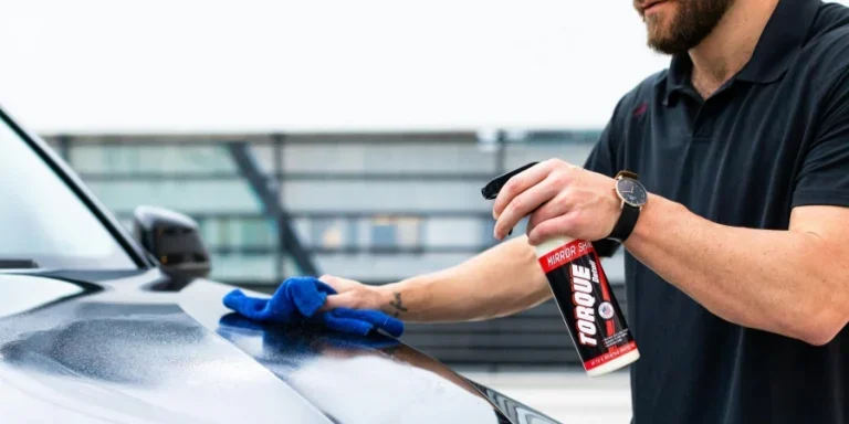 Мужчина чистит капот автомобиля