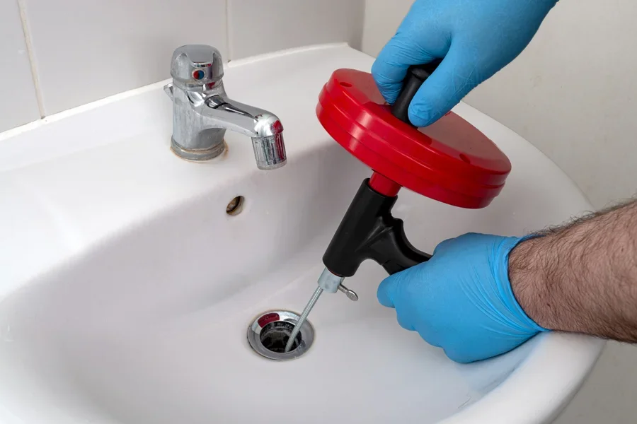 Plumber using snake device to unclog bathroom sink drain