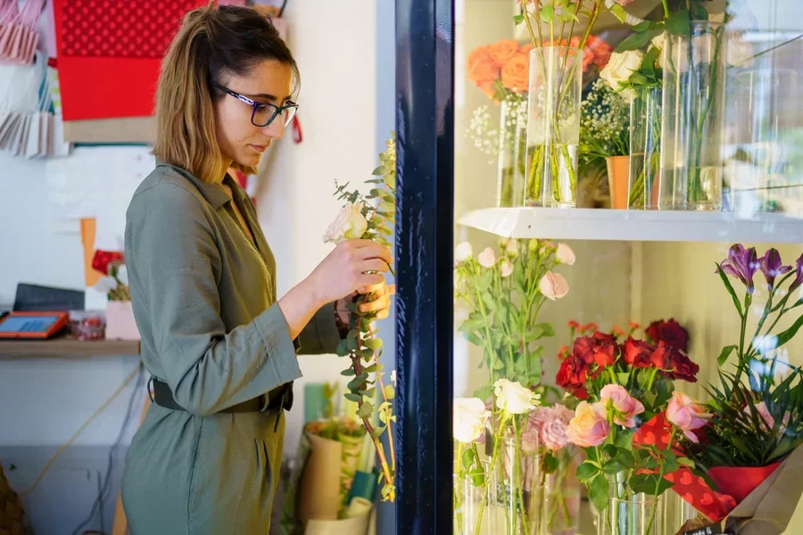 Woman looking at cut flowers inside ornate flower cooler