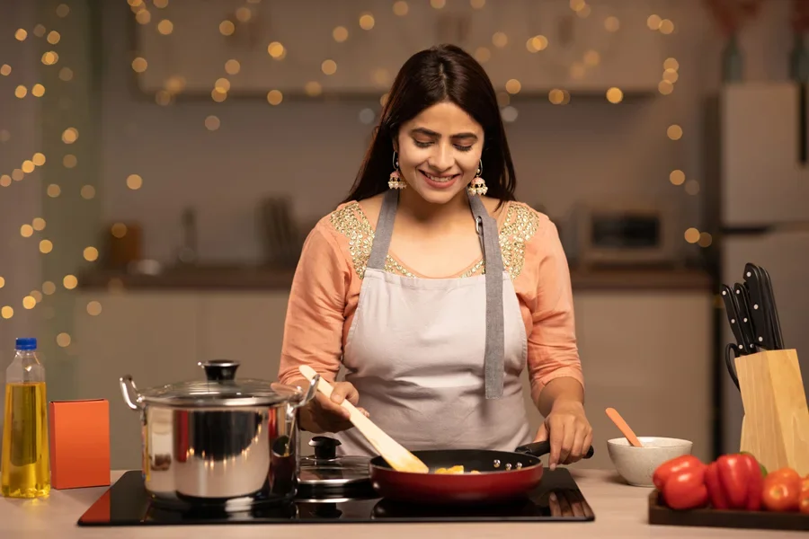 Wanita menggunakan peralatan masak keramik di atas kompor untuk memasak makan malam