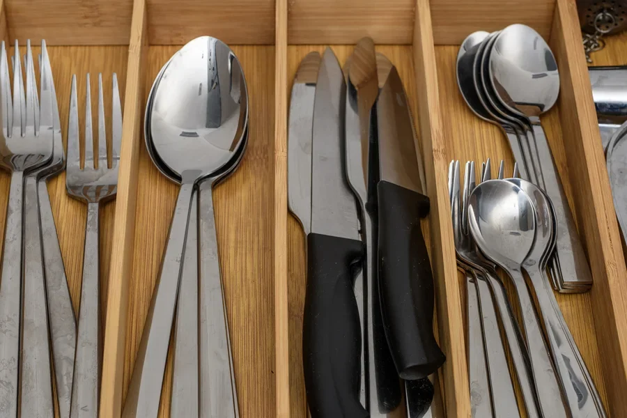 Wooden utensil drawer with knives, forks, and spoons lined up