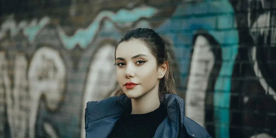 a woman standing in front of a graffiti covered wall