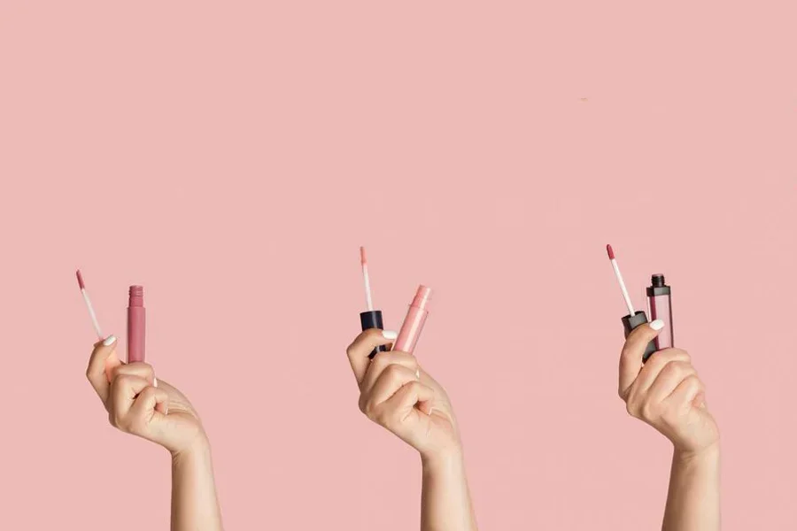 Hands Holding Collection of Lip Glosses