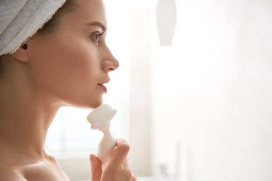 Señora limpiando su rostro con un cepillo dérmico