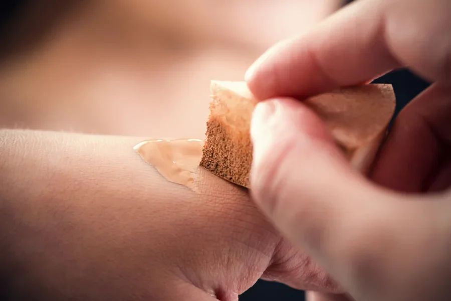 Make-up-Schwamm auf der Hand zum Verblenden der Foundation