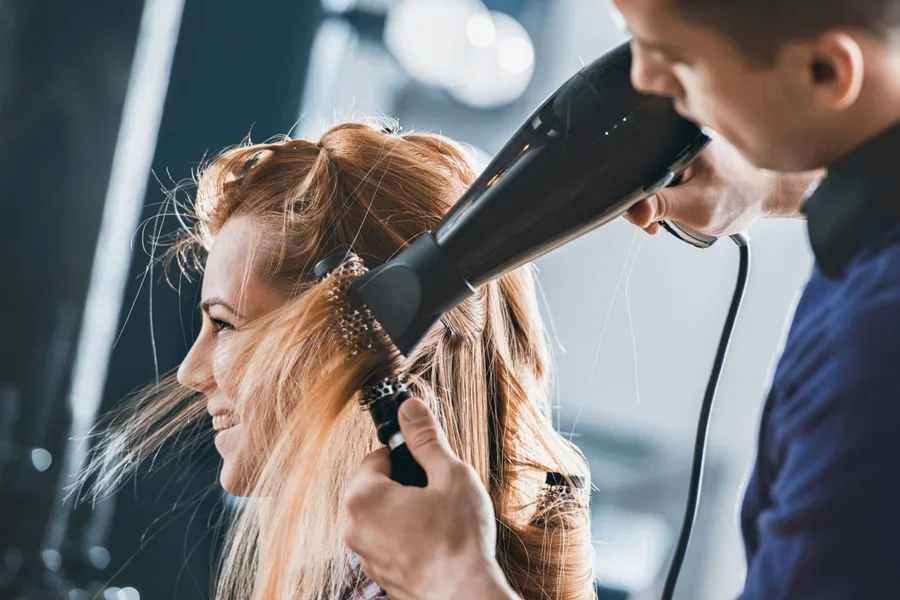 Femme souriante se faisant coiffer dans un salon de coiffure