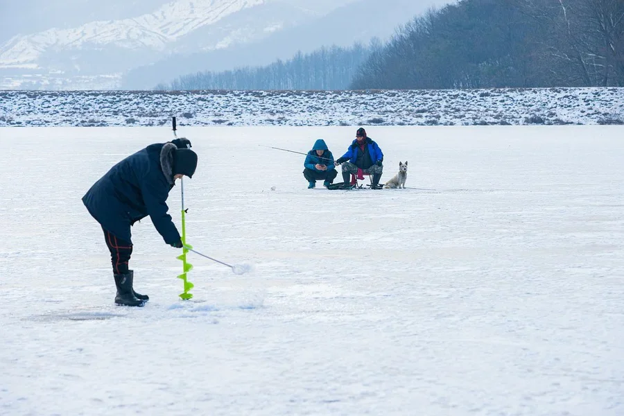 Three people fishing in ice
