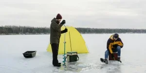 Two people working in a snow fishing setup