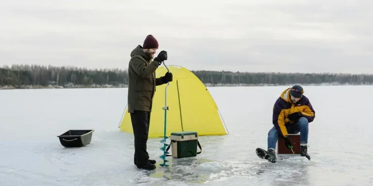 Two people working in a snow fishing setup