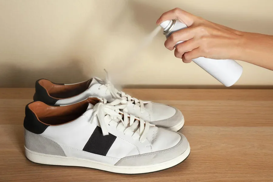 Woman Spraying Deodorant over Pair of Shoes