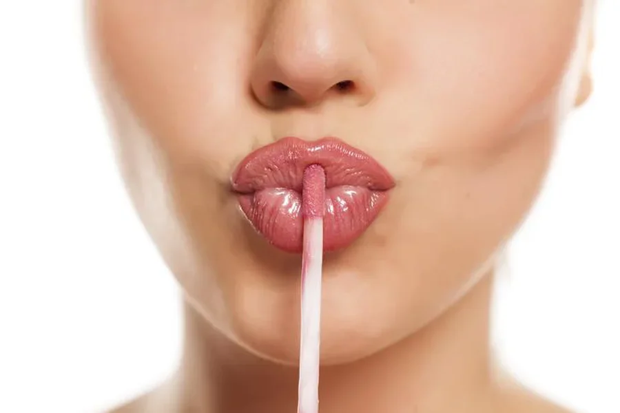 Young Woman Applying a Lip Gloss on Her Lips