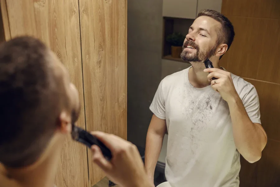 Un hombre de pie en el baño afeitándose la barba