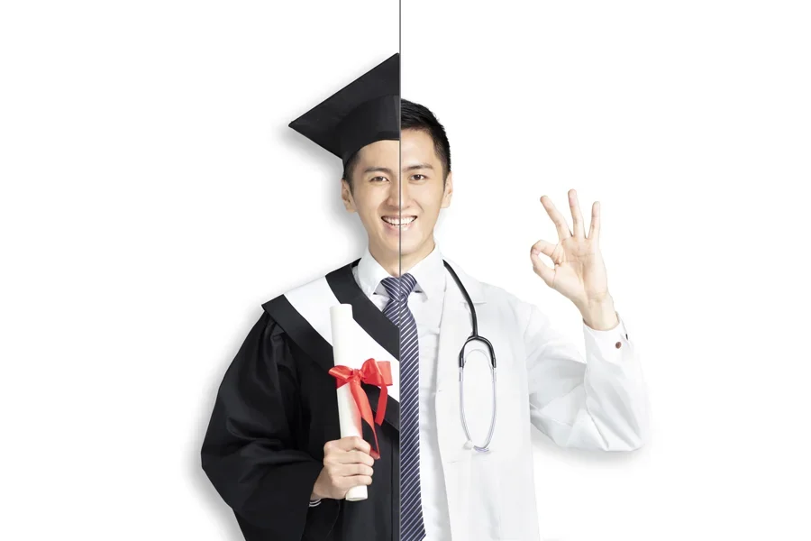 Hombre asiático con toga de graduado y uniforme de médico sosteniendo su diploma