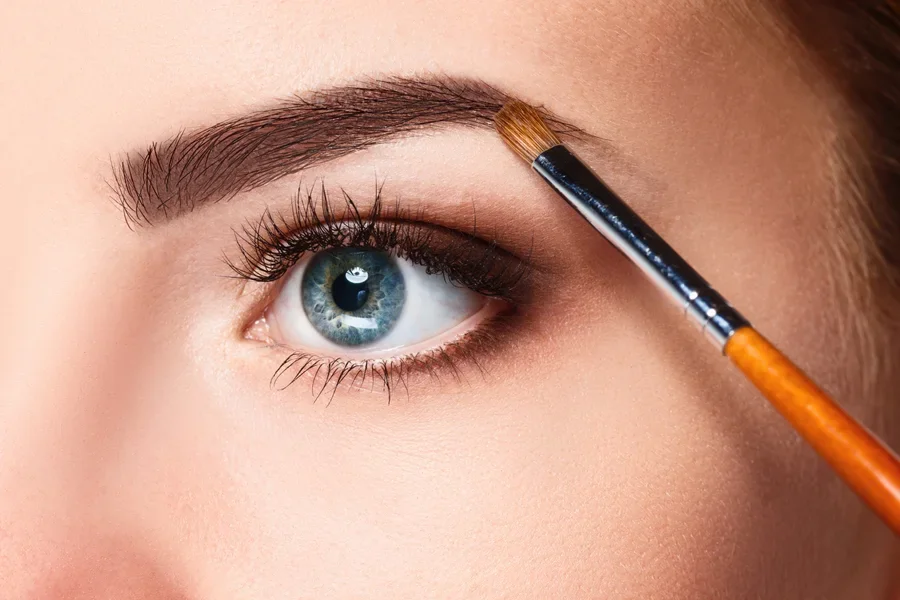 Close up of brown eyebrow with brush adding makeup to it